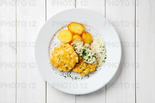 Top view of ground chicken meat cutlet with fried potato wedges and creamy sauce with bacon on white wooden table