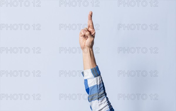 Hand gesturing the letter R in sign language on an isolated background. Man's hand gesturing the letter R of the alphabet isolated. Letter R of the alphabet in sign language