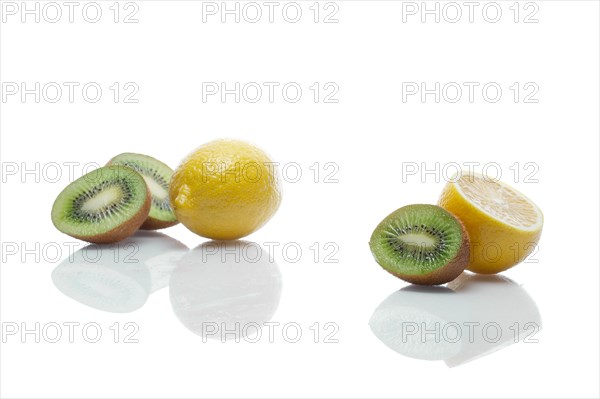 Lemons and kiwi with reflection on white glass table