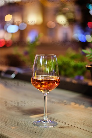 Glass of rose wine on bar counter with night city view on bacground