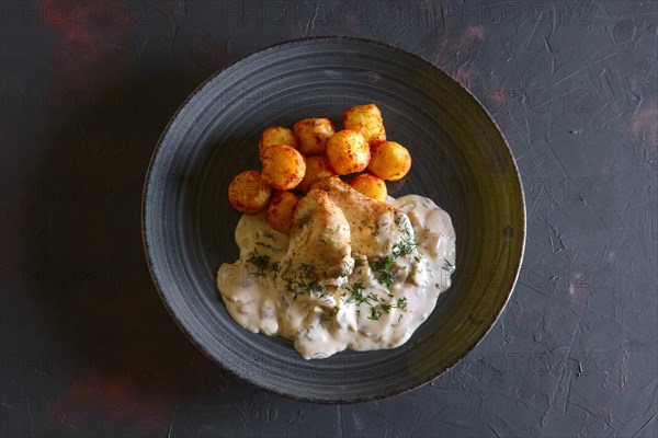 Fried potato balls and white fish fillet with creamy sauce