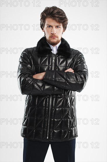 Brutal handsome unshaven man with beard and moustache in waterproof coat with fur collar