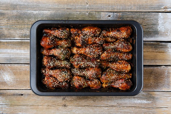 Overhead view of baked chicken legs with spicy sauce on a baking tray