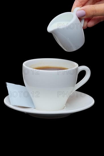 Pouring milk in coffee. Photo with clipping path isolated on black background