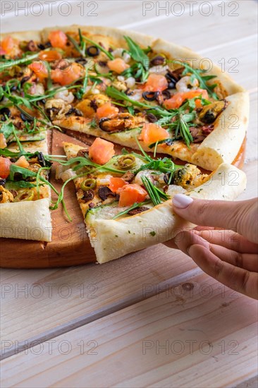 Hand picking slice of pizza with shrimps