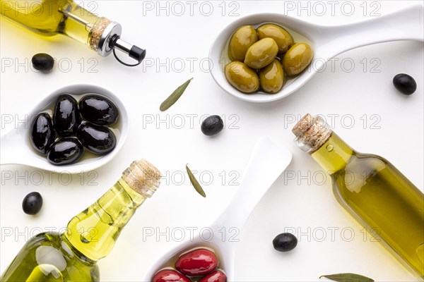 Flat lay yellow red black olives spoons with oil bottles