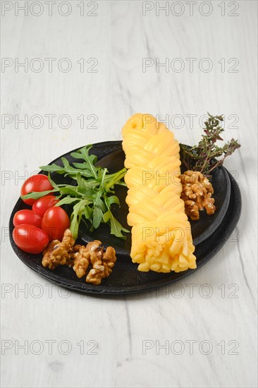 Smoked braided cheese with walnuts and tomatoes on a plate