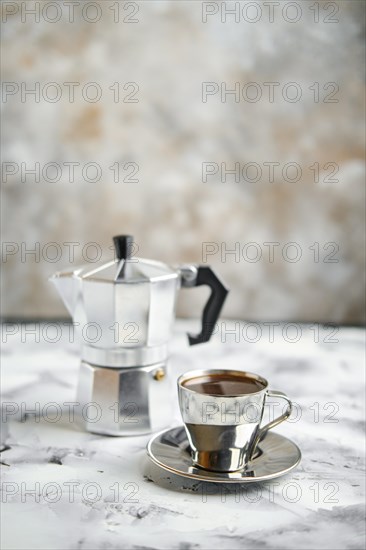 Geyser coffee maker and metal cup on abctract background