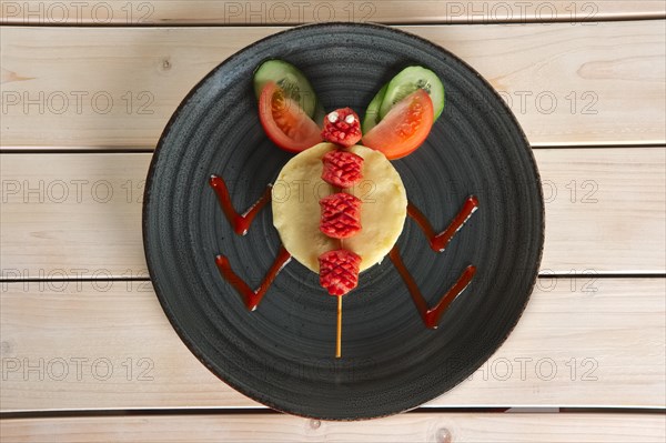 Funny meal for children. Mashed potato with fried sausage on skewer with tomato and cucumber