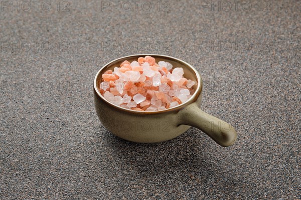 Pink Himalayan salt in a ceramic bowl on stone background