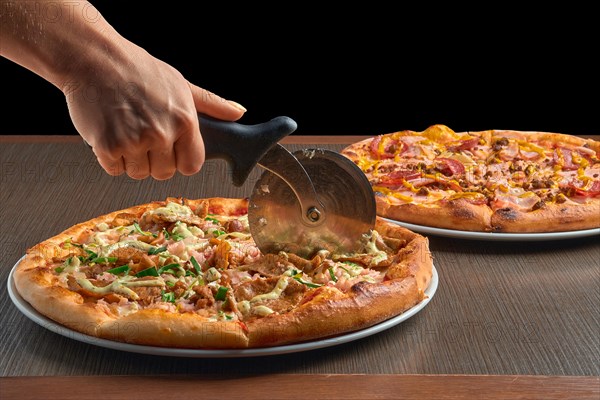 Hand with knife citting pizza