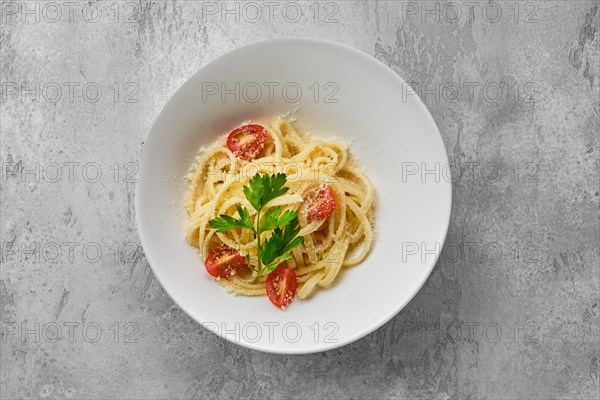 Top view of plate with noodles with parmesan cheese and tomato