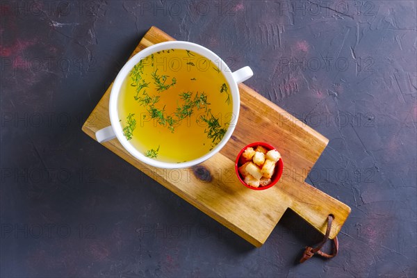 Plate with clear soup and pieces of white bread crouton