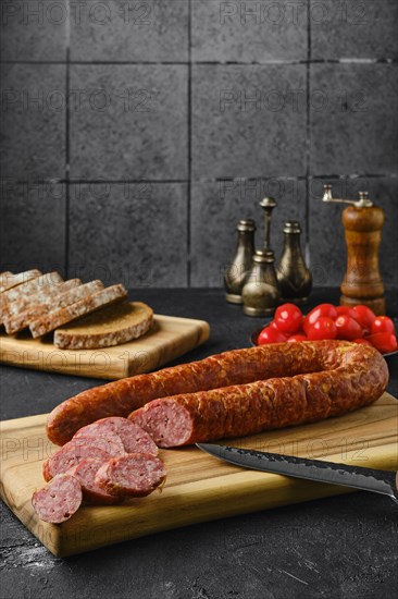 Smoked beef sausage rings on wooden cutting board on kitchen table