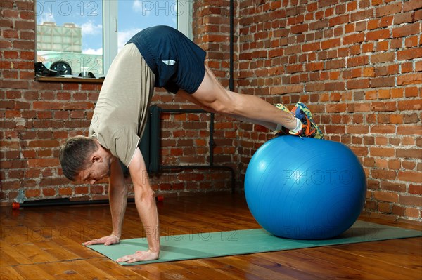 Athletic man doing balancing exercises with the gym ball. Fitness workout