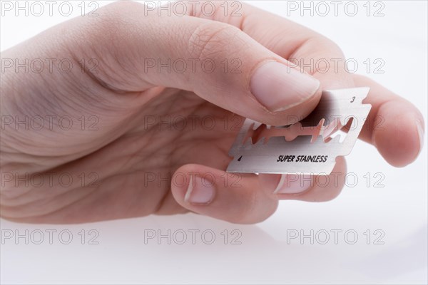 Hand holding a razor blade on a white background