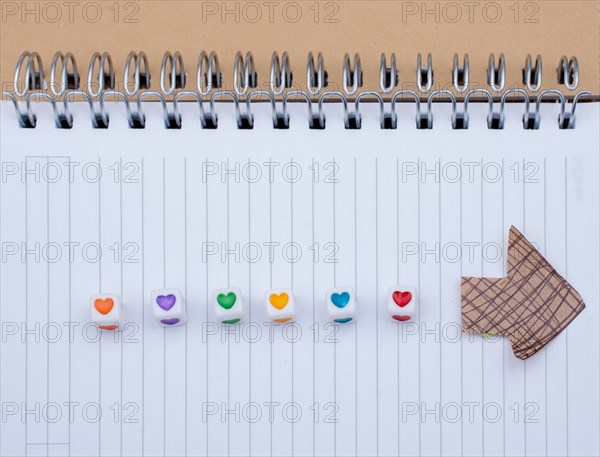 Love cubes and paper arrow on a notebook on canvas