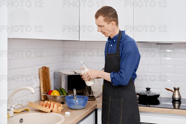 Man pouring milk in a bowl with beaten eggs to make an omelet