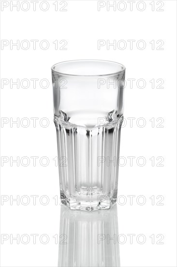 Empty transparent faceted glass with reflection on white background