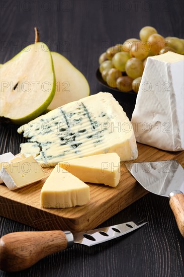 Assortment of cheese and snack for wine on dark wooden table