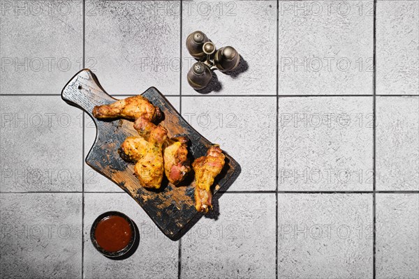 Overhead view of baked crispy chicken legs under hard light