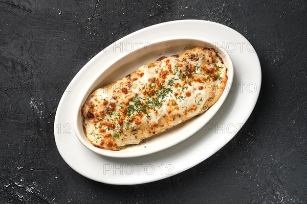 Top view of pancakes with meat and cheese baked in oven on dark background