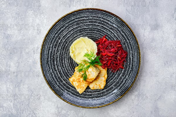 Top view of fried hake in breading with mashed potato and roasted beetroot