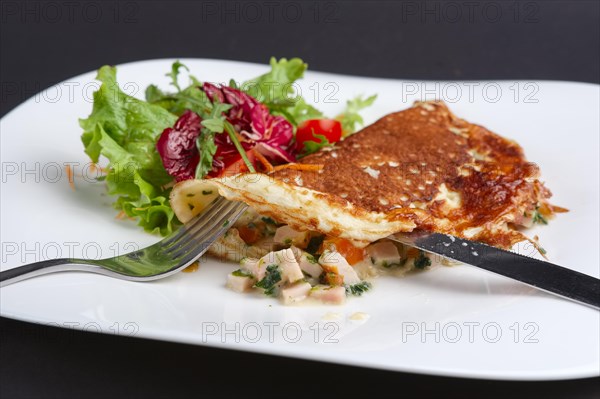 Cutting with knife omelet with ham and vegetables