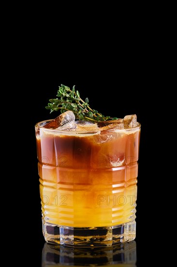 Espresso and tonic with orange syrup and thyme on black background