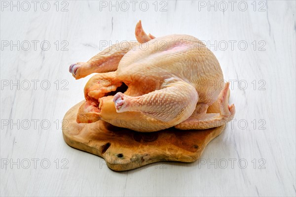 Fresh raw whole farm chicken on wooden cutting board