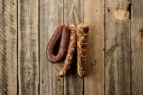 Assortment of dried meat and sausages hanging on a barn wall