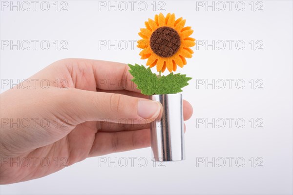 Hand holding a glass bottle with a fake flower in it