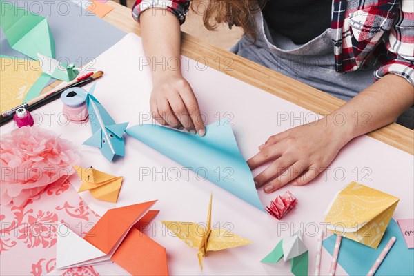 Female artist folding origami paper making beautiful craft