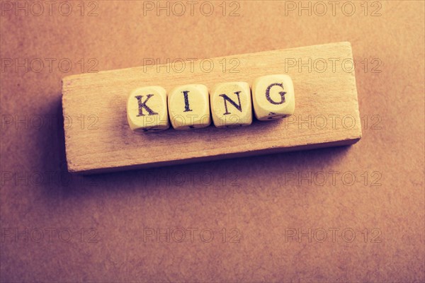 King wording with wooden cubes on a piece of wood