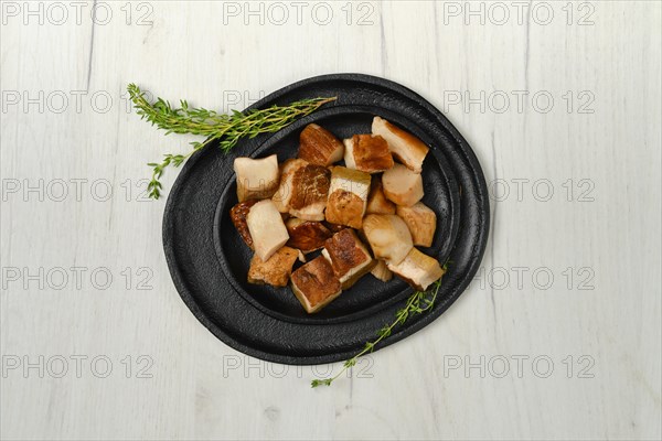 Overhead view of frozen fresh boletus cut on pieces on black stone plate