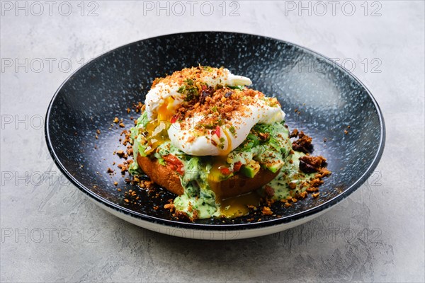 Poached egg on a bun with avocado on a plate