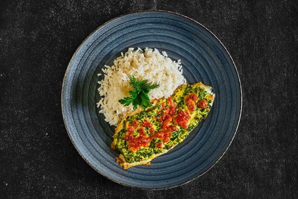 Top view of fried fillet of white fish with spinach and cheese topping and served with rice