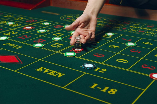 Casino roulette table with chips and cards. Winning combination. Hand of Croupier behind gambling table