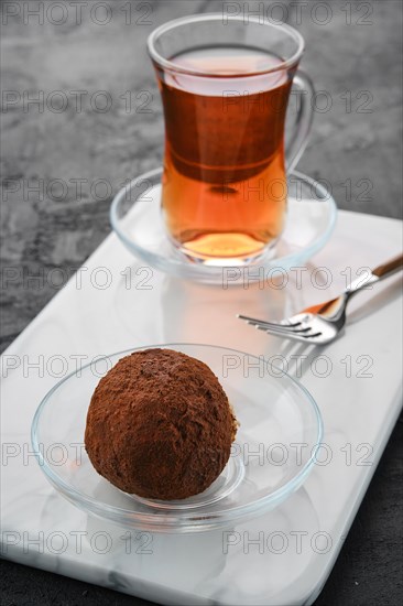 Closeup view of chocolate biscuit dough cake and a cup of tea on a table