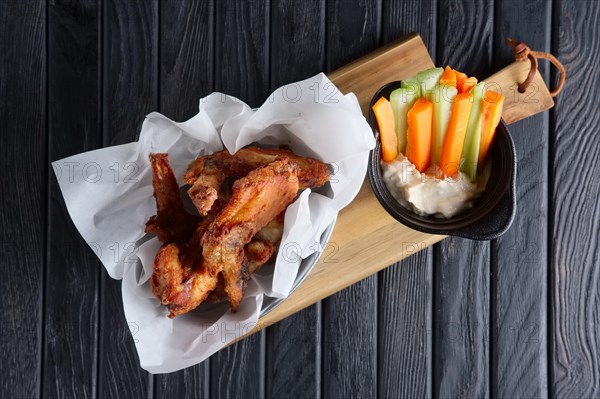 Snack for beer. Spicy chicken wings with fresh carrot and celery and sauce