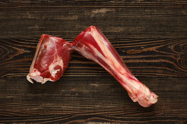 Overhead view of raw deer shank over dark wooden background