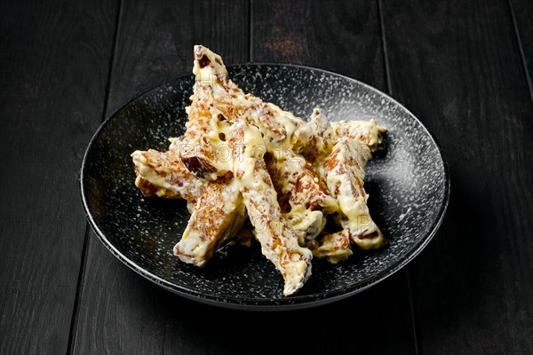 Salty bread sticks covered with melted cheese on a plate