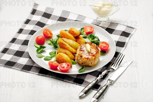 Fried chicken cutlet with potato slices served with tomato cherry and corn salad. Traditional belorussian food