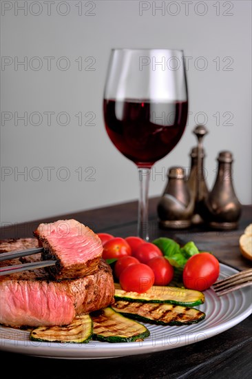 Grilled beef steak and zucchini served with fresh tomato cherry and basil and a glass of red wine