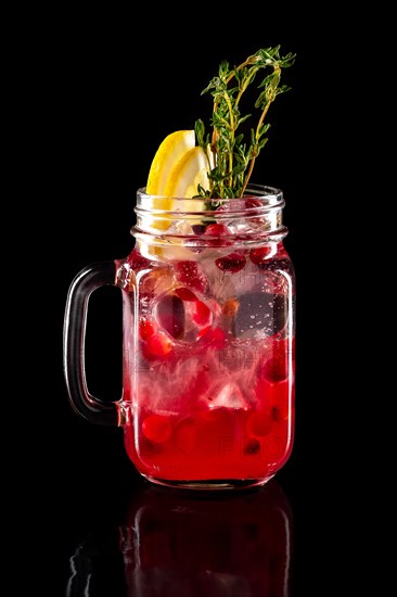 Cold fruit lemonade in mason jar isolated on black background