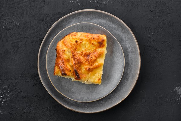 Top view of cheese puff pie from unleavened dough on black wooden background