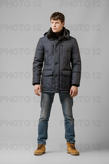 Full length portrait of handsome man in warm winter coat posing in studio