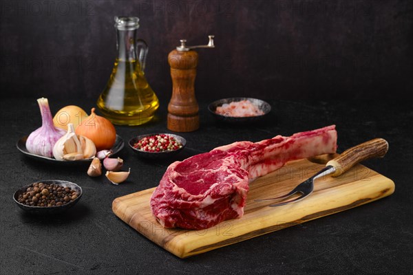 Raw beef cowboy steak with spice and seasoning ready for cooking