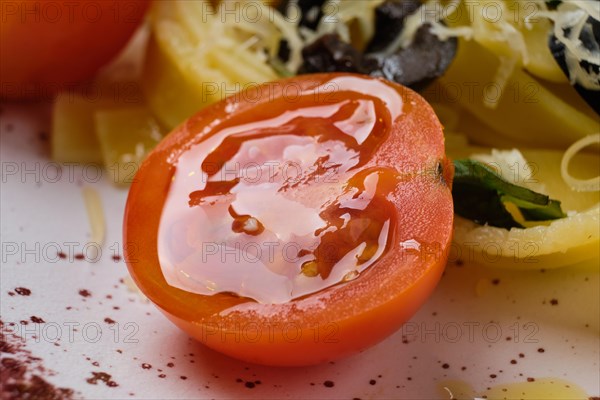 Macro photo with shallow depth of field of half tomato cherry on plate with pasta