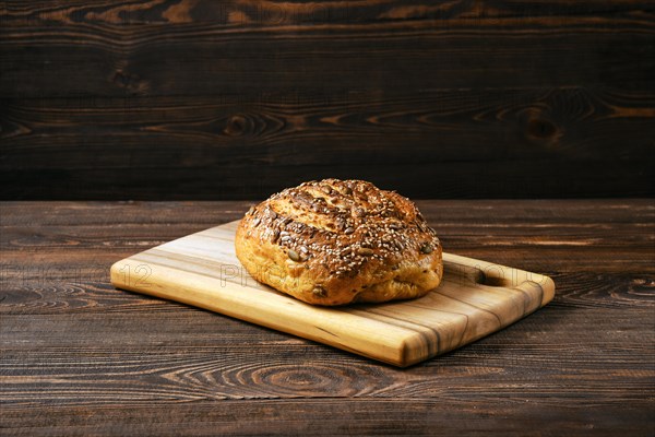 Fresh oats bread with sunflower seeds and sesame on wooden table